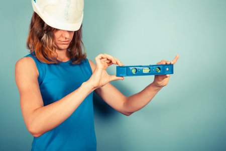 A young female buidler is holding a level