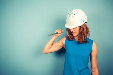 A young female builder is holding a chisel in an aggresive mannerの写真素材