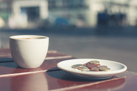 Coins on a saucer outside on a cafe tableの写真素材