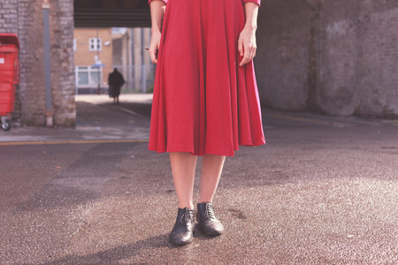A young woman wearing a red dress is standing in the streetの写真素材