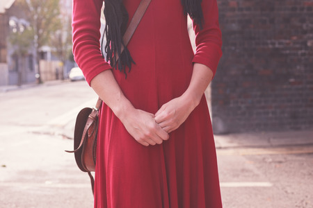 A young woman wearing a red dress is standing in the streetの写真素材