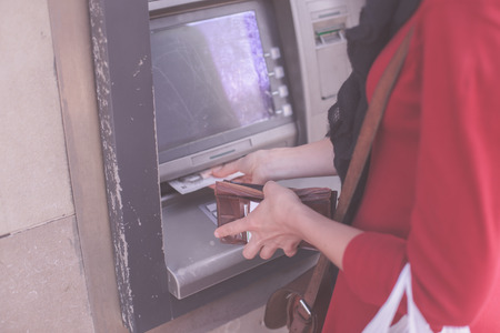 A young woman is withdrawing money from an ATMの写真素材