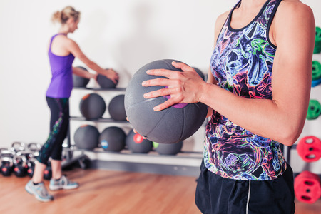 A young woman is standing in the gym and is holding a medicine ballの写真素材