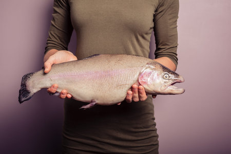 A young woman is holding a rainbow trout
