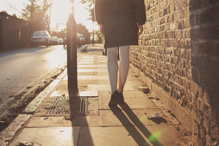 A young woman is walking into the sunset on an autumn day in the cityの写真素材
