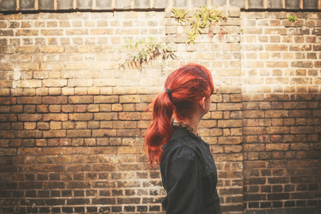 A young redhead woman is walking in a cobbled alley in the autumn on a sunny dayの写真素材