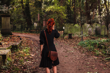 A woman is walking in a cemetery and is talking on the phoneの写真素材