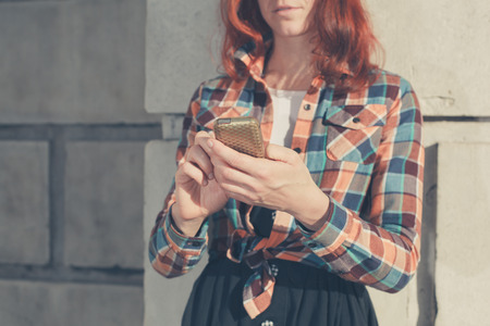 A young woman is standing in the street and is using her phoneの写真素材