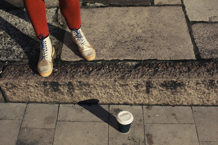 A woman's feet and a paper cup in the streetの写真素材