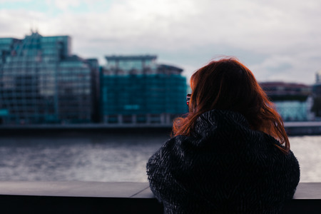 A young woman is looking at the river Thames in Londonの写真素材