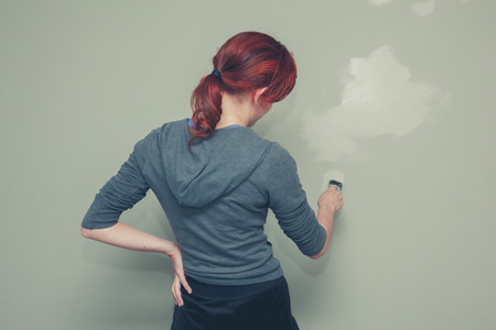 A young woman is painting a wall greenの写真素材