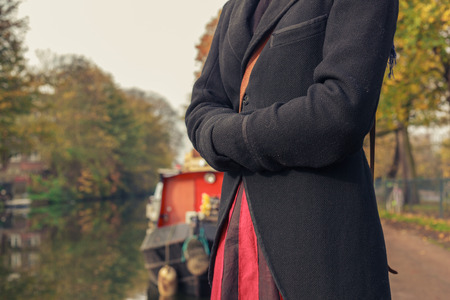 A woman is standing by the canal next to a houseboatの写真素材