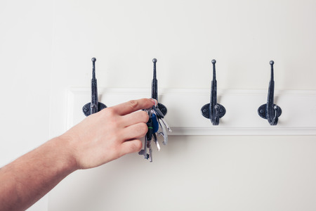 A male hand is hanging keys on a hookの写真素材