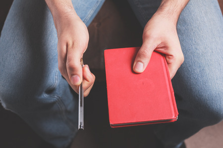 A man is sitting holding a pen and a notebookの写真素材