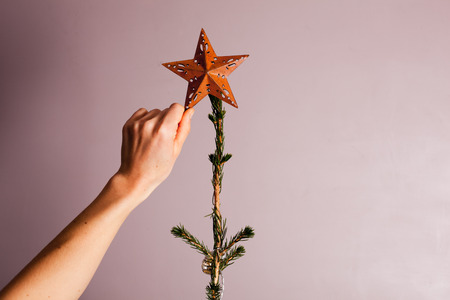 A hand is putting a decorative  star on a christmas treeの写真素材