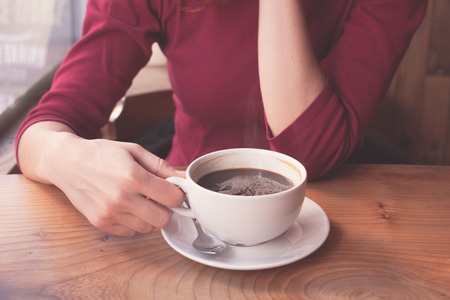 A young woman is having a cup of coffee by the window in a cafeの写真素材