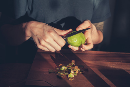 Close up on the hands of a woman as she is cutting a kiwiの写真素材