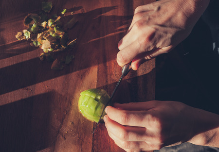 Close up on the hands of a woman as she is cutting a kiwiの写真素材