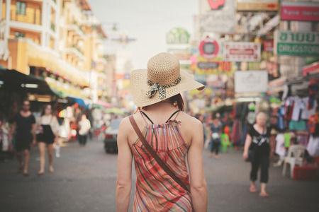 Rear view of a young woman walking the famous backpacker street Khao San in Bangkok, Thailand