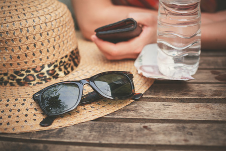 A hat and a pair of sunglasses on a table outside with a woman in the backgroundの写真素材