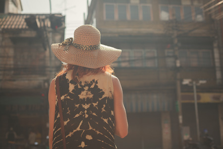A young woman wearing a hat is walking in the streets of an asian countryの写真素材