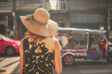 A young woman wearing a hat is walking in the streets of an asian countryの写真素材
