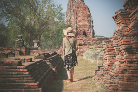 A young woman is exploring the ancient ruins of a buddhist temple cityの写真素材