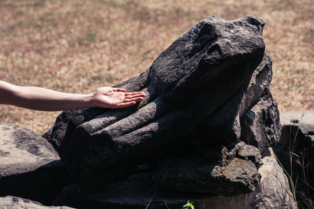 The hand of a woman is touching the hand of an ancient statueの写真素材