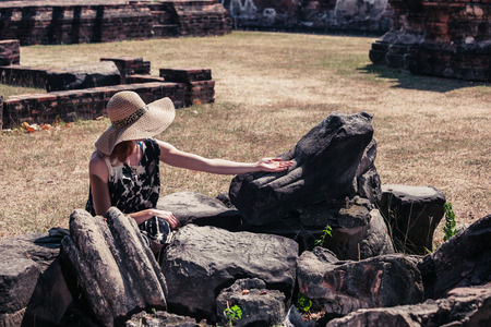 A young woman is touching the ancient ruins of a buddha statueの写真素材