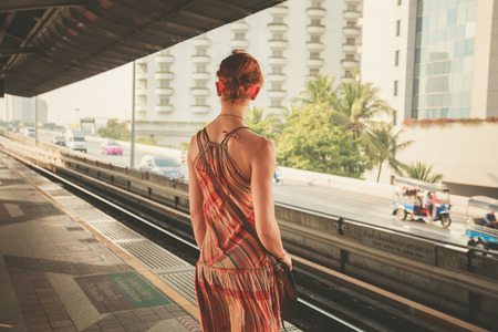 A young woman is standing on a train platformの写真素材