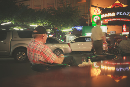 Bangkok - January 5, 2015. An old man is relaxing in the Red light district of Nana in Bangkok, Thailandのeditorial素材