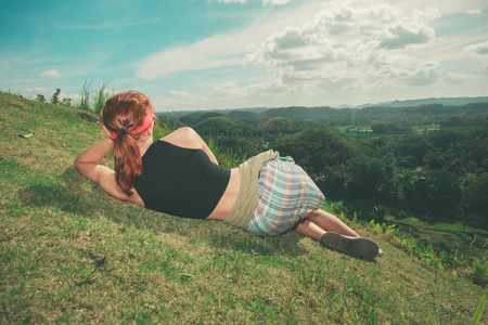 A young woman is lying on the hillside and is admiring the view of the chocolate hills in Bohol, Philippinesの写真素材