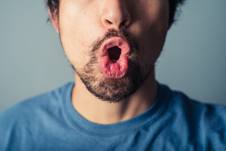 A young man with a beard is pulling silly facesの写真素材