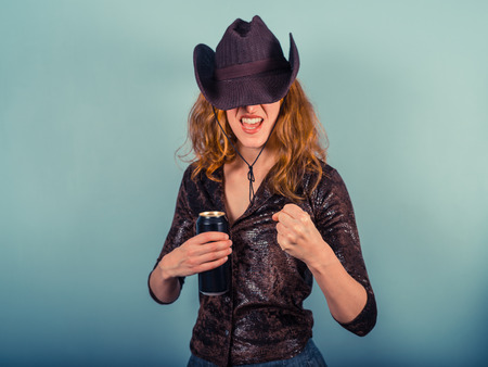 A drunk woman wearing a cowboy hat is raising he fist and is looking aggressiveの写真素材