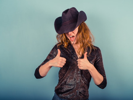 A young woman wearing a cowboy hat is giving two thumbs upの写真素材