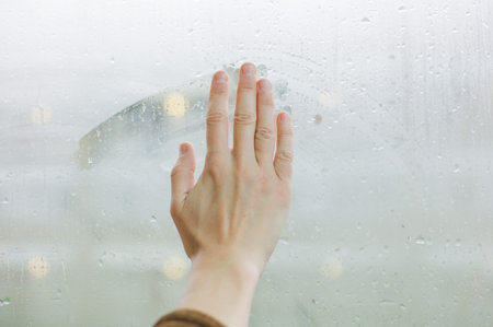 A female hand is wiping the dew of a window