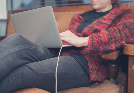 A young woman is using her laptop at home in her living room