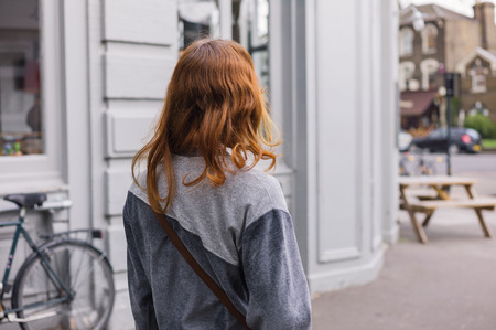 A young woman is walking in the street outside a cafeの写真素材