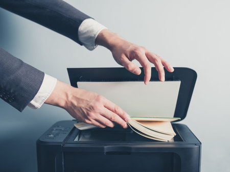The hands of a young businessman is placeing a book on a flatbed scanner in preperation for copying...
