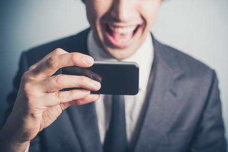 A happy young businessman is using his smartphoneの写真素材