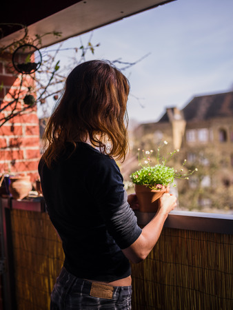 A young woman is attending to her plants on a balconyの写真素材