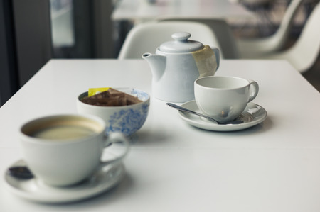A teapot and two cups on a table in a cafeの写真素材