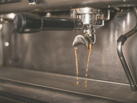 Detail of professional coffee machine with coffee brewing and dripping from the tapの写真素材