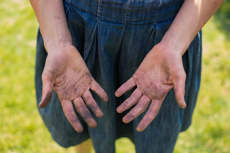 A young woman is showing of her dirty hands covered in dirt from gardeningの写真素材