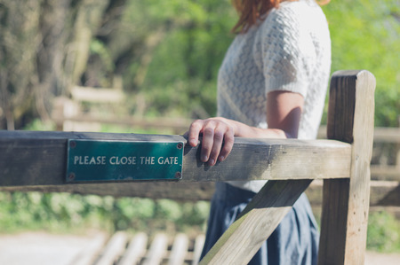A young woman is opening a wooden gate in the forestの写真素材