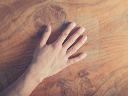 A young male hand on a wooden tableの写真素材