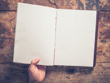 A male hand and a big notepad on a wooden tableの写真素材