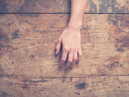 A young female hand on a wooden tableの写真素材