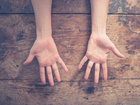 Close up on a woman showing her palms at a wooden tableの写真素材