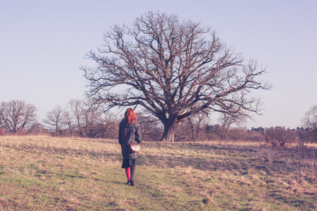 A young woman with red hair is walking in the countryside on a winter dayの写真素材